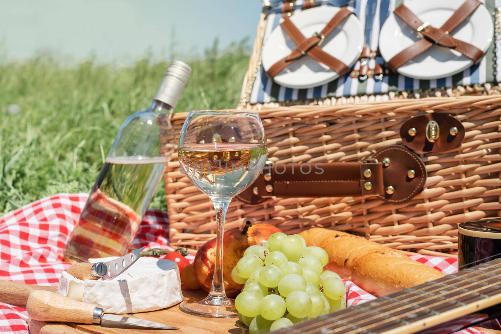 Closeup of picnic basket with drinks and food on the grass. Nice picnic on sunny summer day, fun and leisure