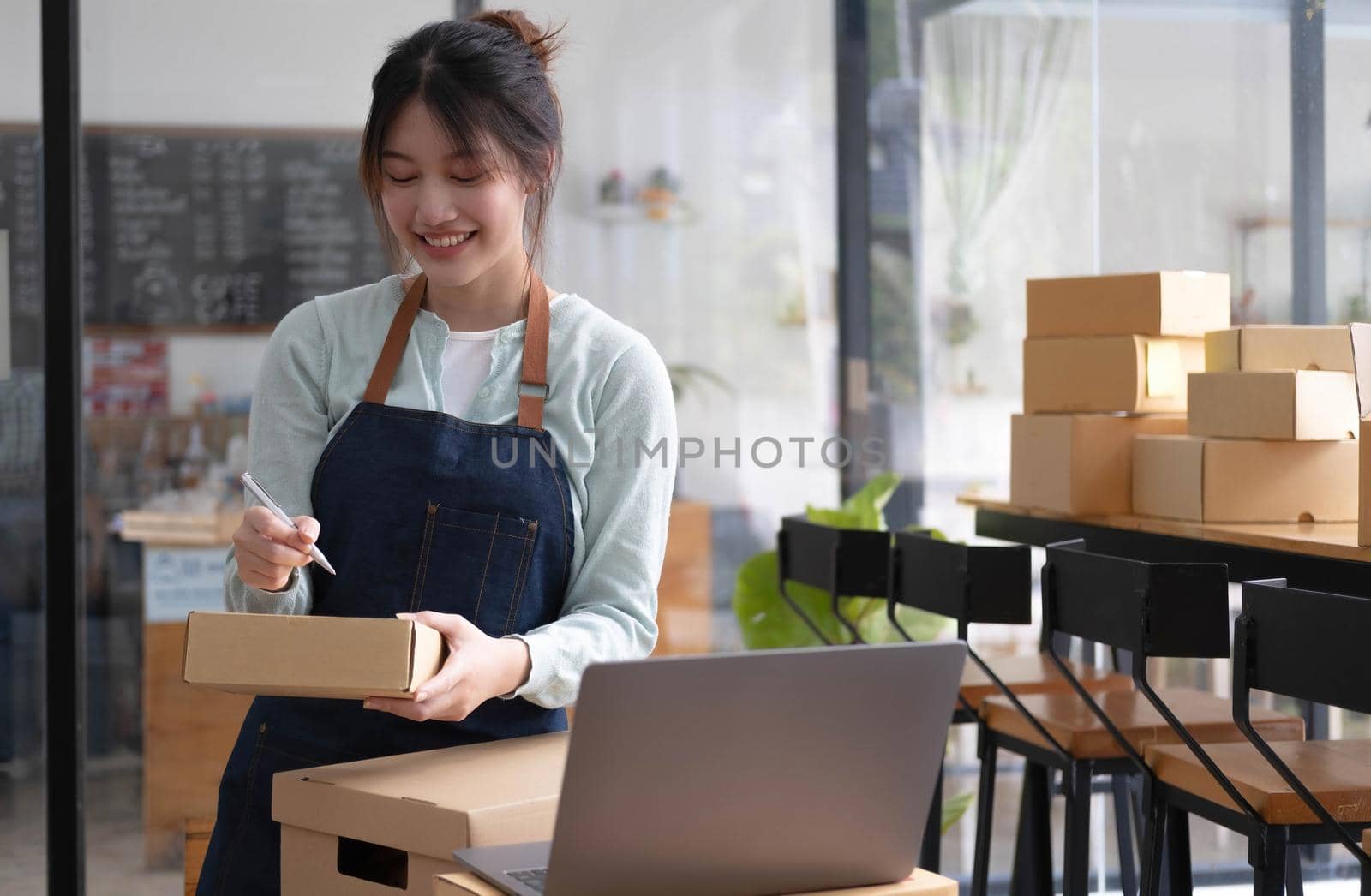 Shipping shopping online ,young start up small business owner writing address on cardboard box at workplace.small business entrepreneur SME or freelance asian woman working with box at home by wichayada