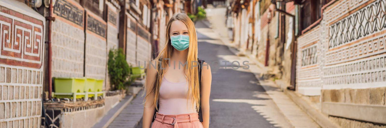 Young woman tourist in medical mask in Bukchon Hanok Village is one of the famous place for Korean traditional houses have been preserved. Travel to Korea Concept Tourists fear the 2019-ncov virus. Medical masked tourists BANNER, LONG FORMAT by galitskaya