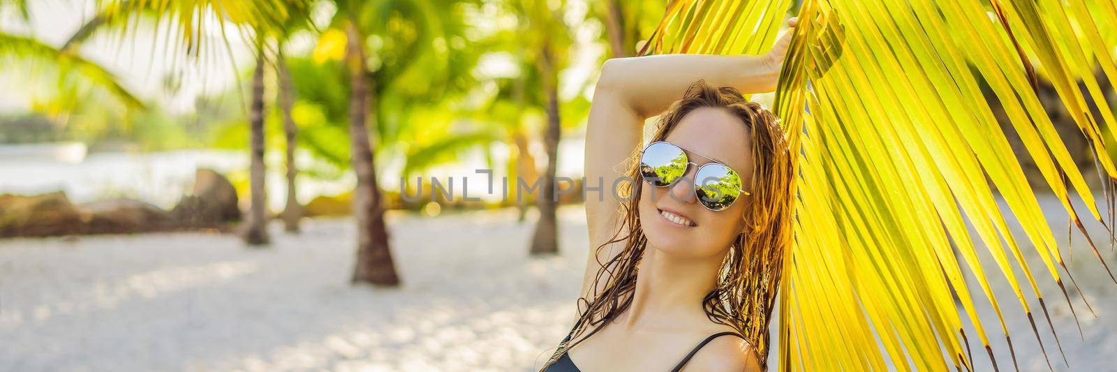 young beautiful woman in swimsuit on tropical beach, summer vacation, palm tree leaf, tanned skin, sand, smiling, happy. Happy traveller woman BANNER, LONG FORMAT by galitskaya