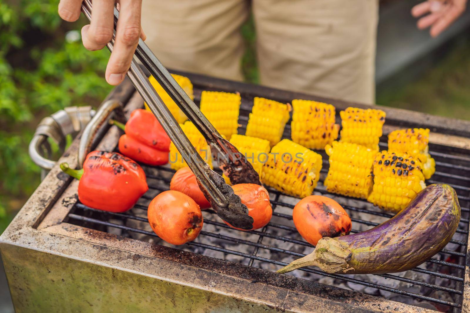 Man with tongs cooking on a back yard barbecue.