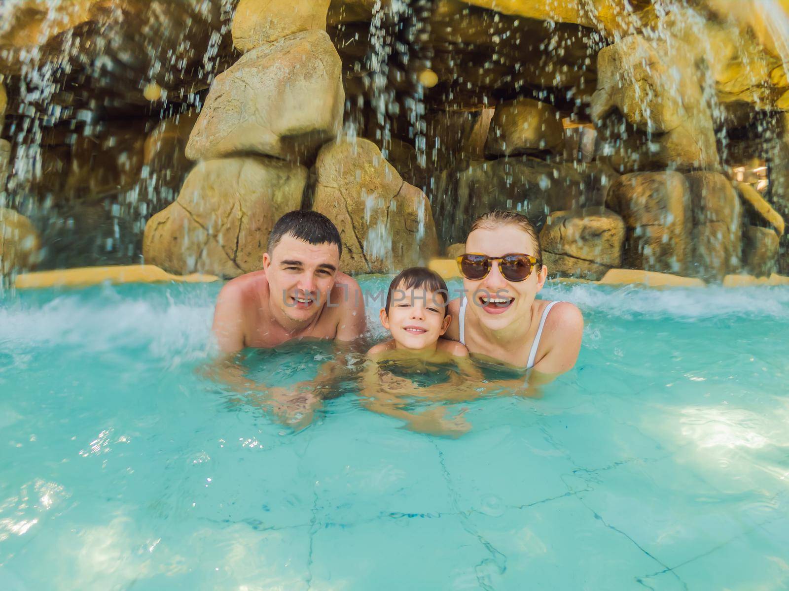 Happy family on holidays swimming with fun in waterfall pool. Active lifestyle, people outdoor travel activity on summer vacation on tropical island.