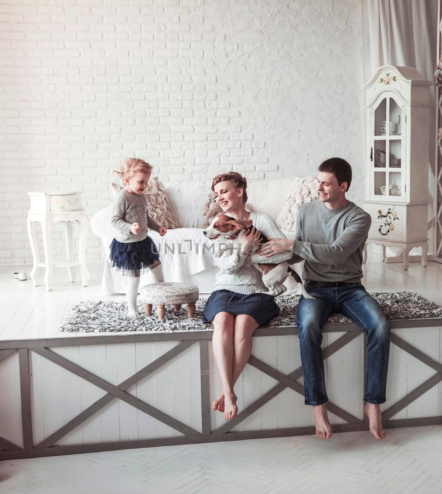 happy parents with five-year-old daughter and their pet dog in the cosy living room