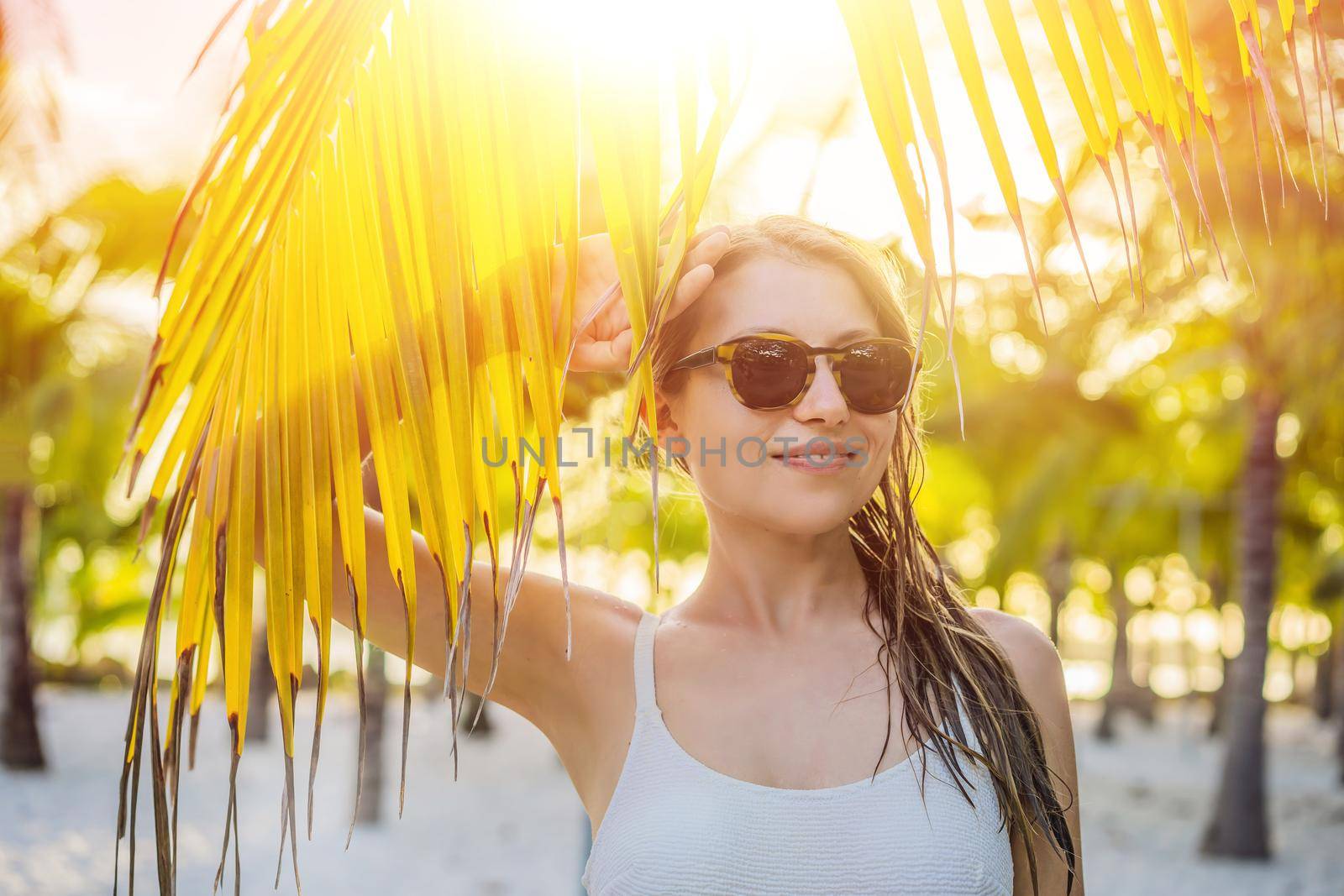 young beautiful woman in swimsuit on tropical beach, summer vacation, palm tree leaf, tanned skin, sand, smiling, happy. Happy traveller woman by galitskaya