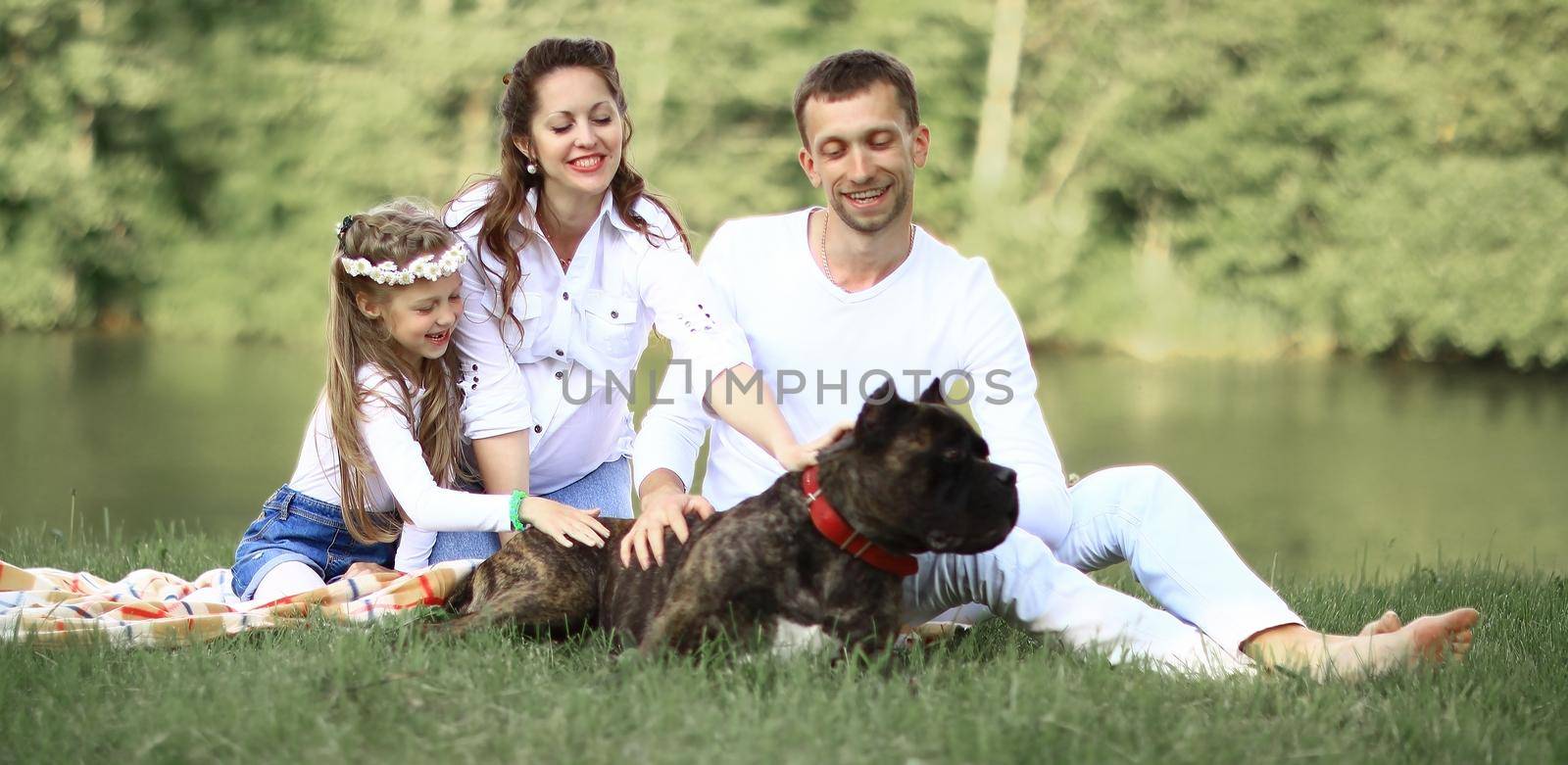 ,little daughter and their dog on a picnic by the river.the photo has a space for your text