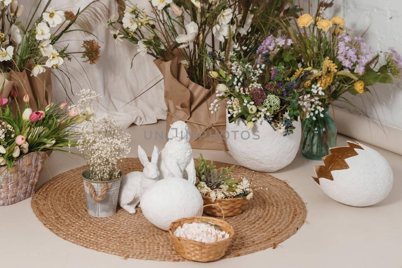 Interior floral Easter composition. Figurines of Easter bunnies and a large eggshell. The concept of home decoration for the Happy Easter holiday