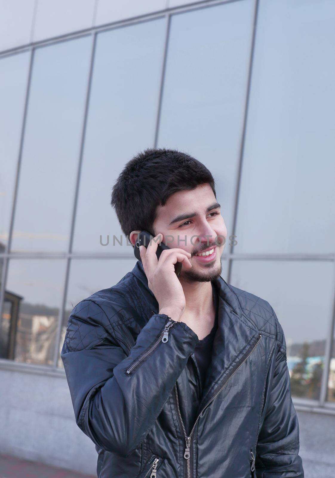 modern young man talking on a mobile phone on the street