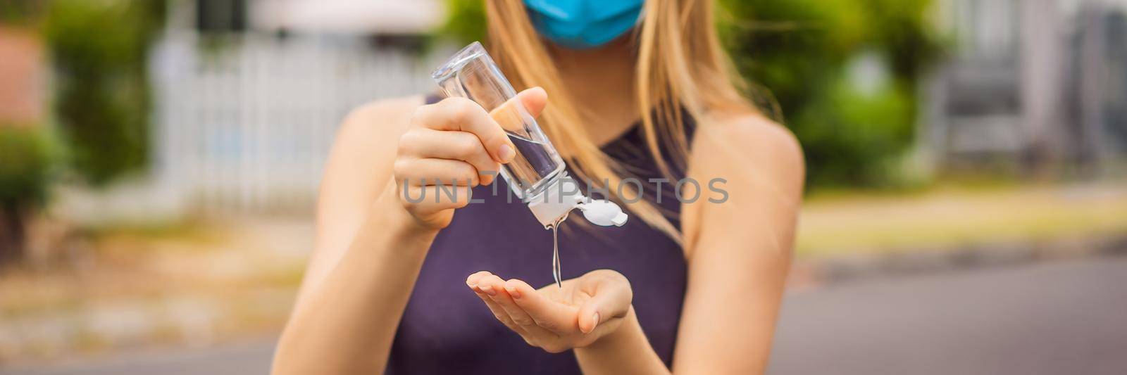 Woman in a small town in a medical mask uses a sanitizer because of a coronovirus epidemic. BANNER, LONG FORMAT