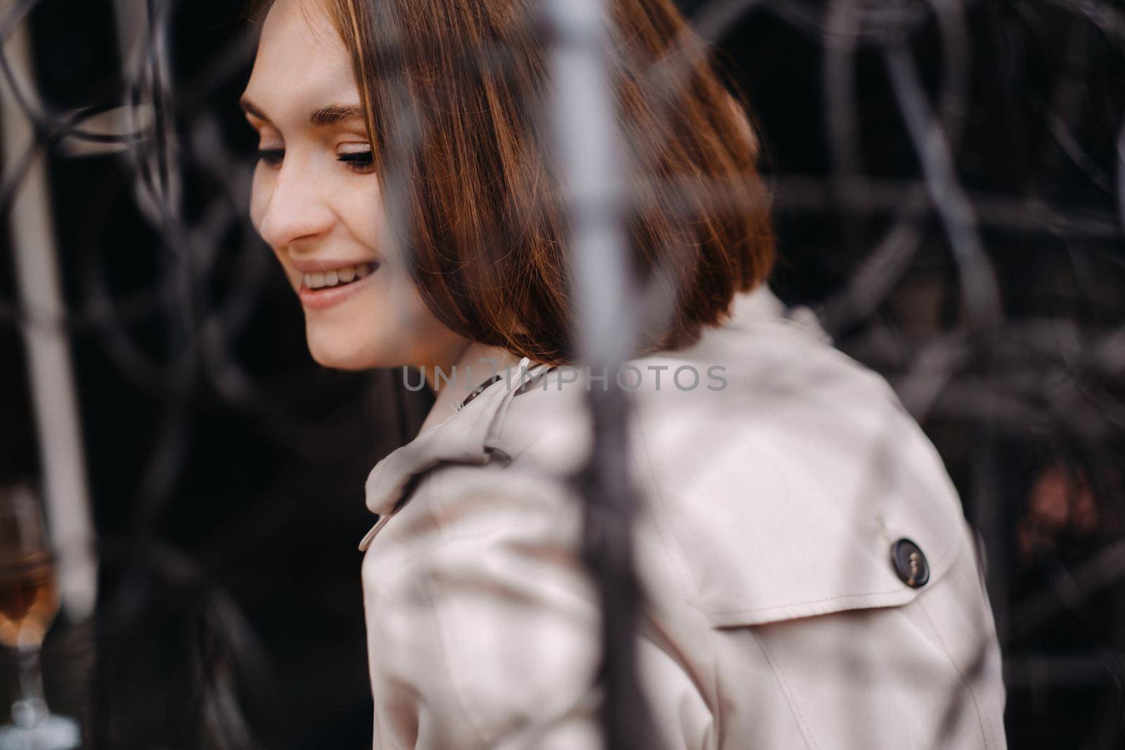 A happy stylish girl In a gray coat is sitting outside in an armchair.