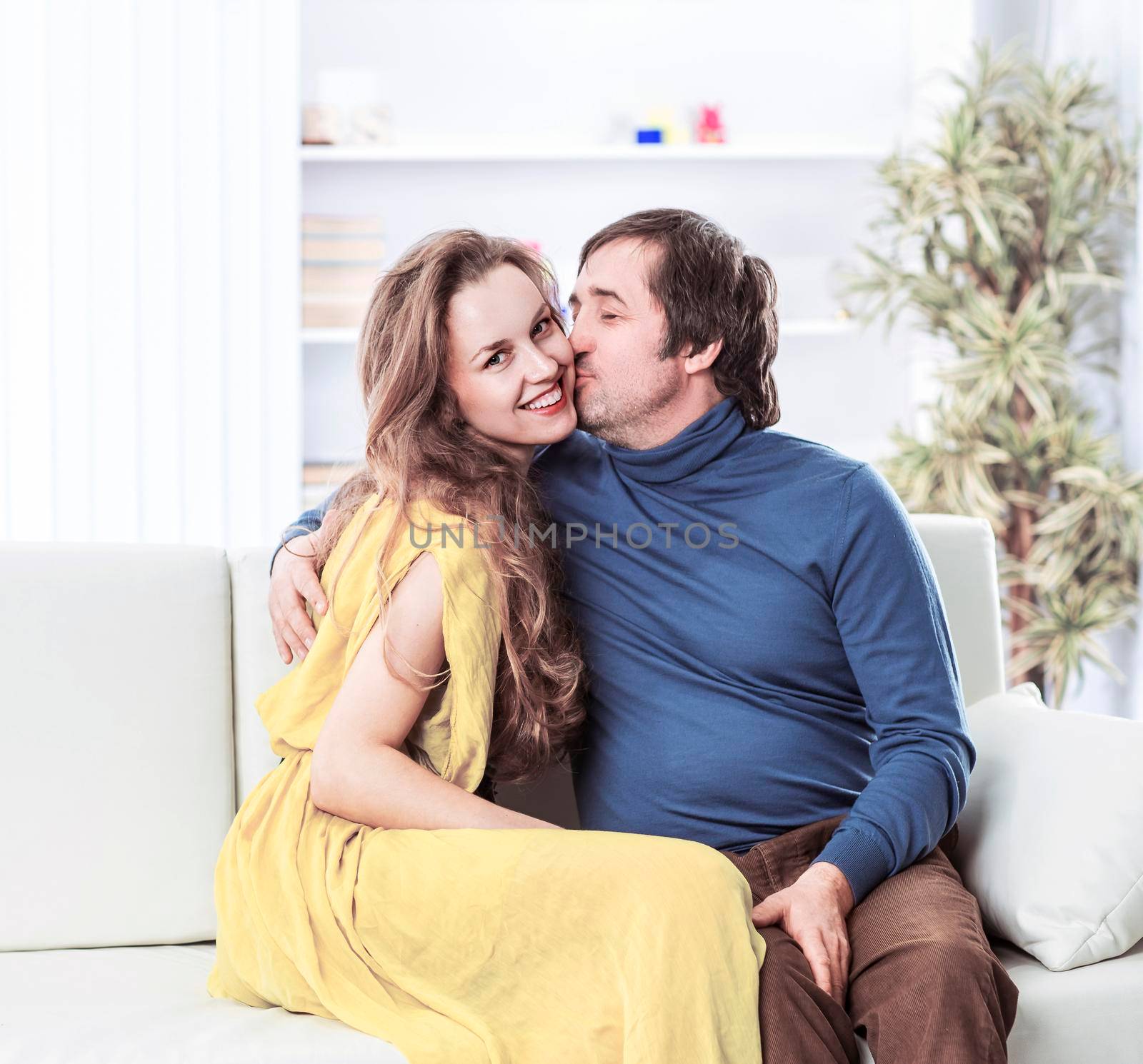 portrait of beautiful couple sitting on the couch in the living room. by SmartPhotoLab