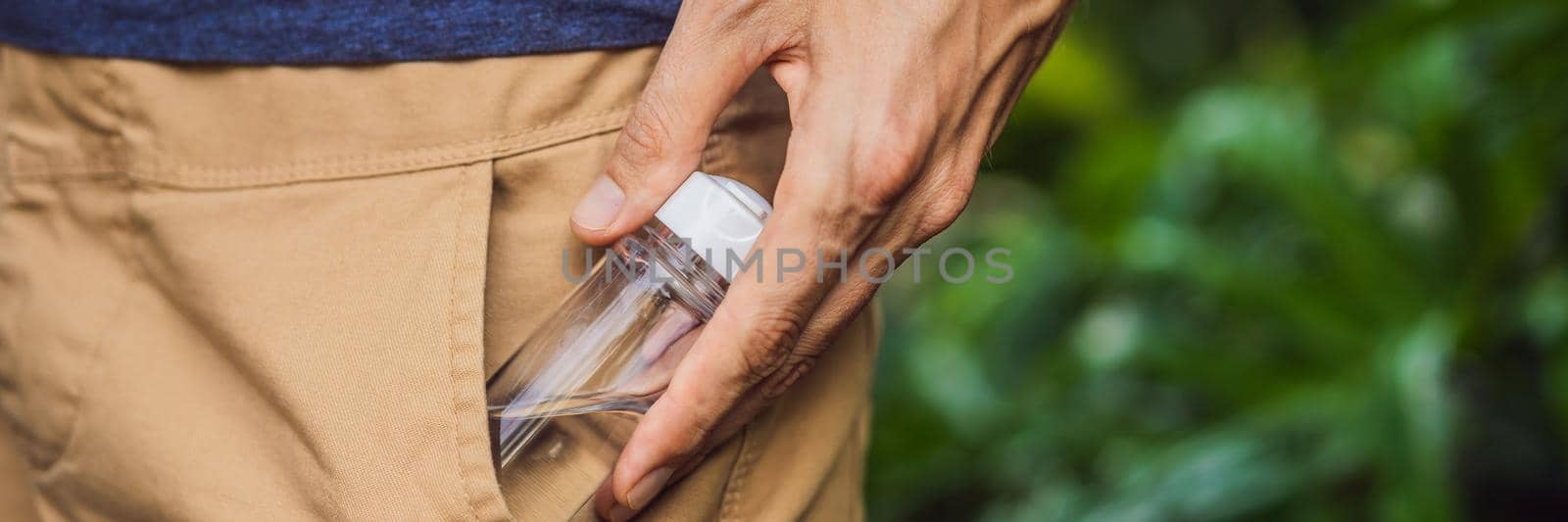 man put a hand sanitizer gel into his trouser pocket when he is going to go outside during corovid -19 outbreak crisis, take care of personal health. BANNER, LONG FORMAT