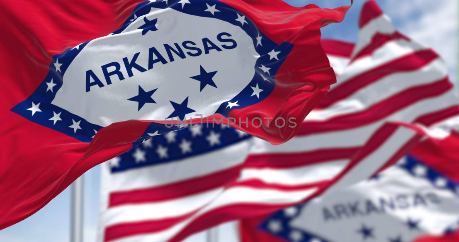 The flags of the Arkansas state and United States waving in the wind. Democracy and independence. US state flag