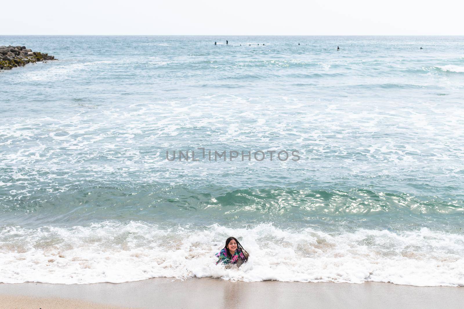 Happy girl sitting on the water's edge in the beautiful beach of San Bartolo south of Lima - Peru. Summer Vacation. by Peruphotoart
