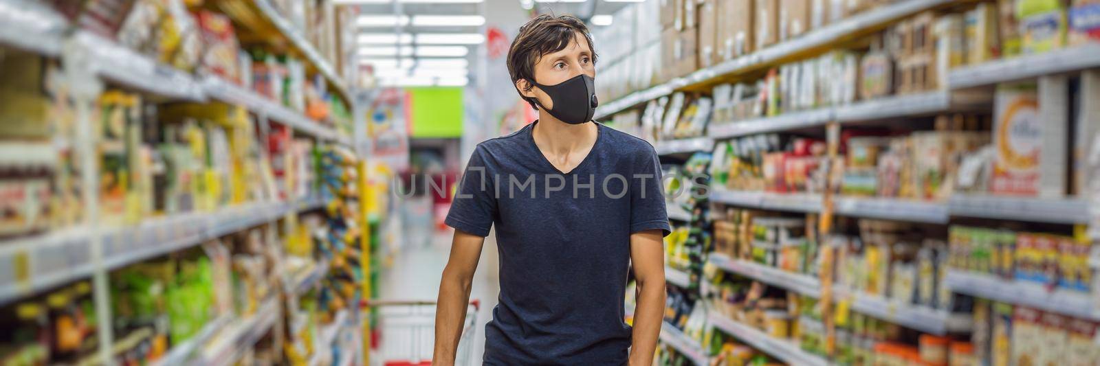 Alarmed man wears medical mask against coronavirus while grocery shopping in supermarket or store- health, safety and pandemic concept - young woman wearing protective mask and stockpiling food. BANNER, LONG FORMAT