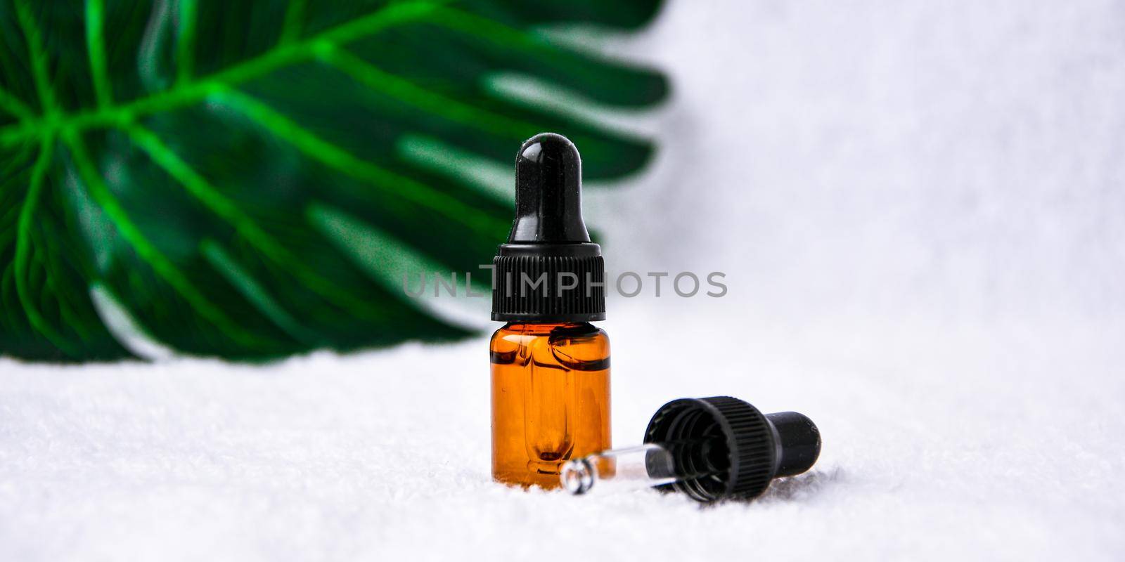 Dropper glass bottle skincare essential oil product for mock up in minimal style on white background with monstera leaf. Copy space. by anna_stasiia