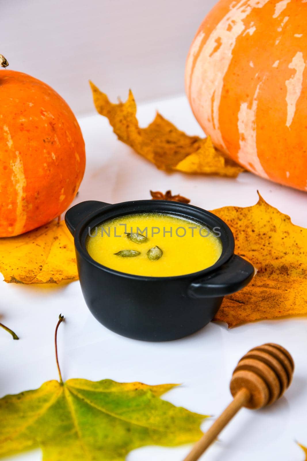 Autumn food. Pumpkin puree soup, leaves. Autumn harvest, pumpkins, leaves on grey as abstract background. Thanksgiving day. by anna_stasiia