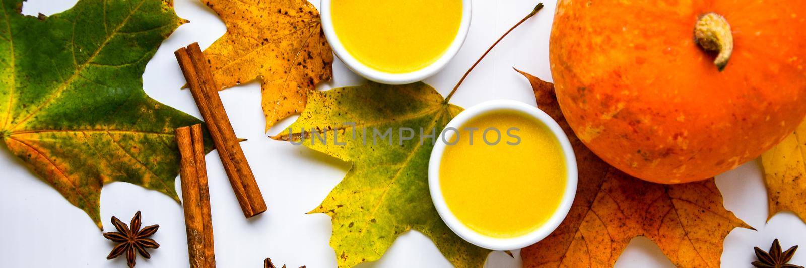 Autumn food. Pumpkin puree soup, leaves. Top view. Autumn harvest, pumpkins, leaves on grey as abstract background. View from above. Thanksgiving day. Flat lay.