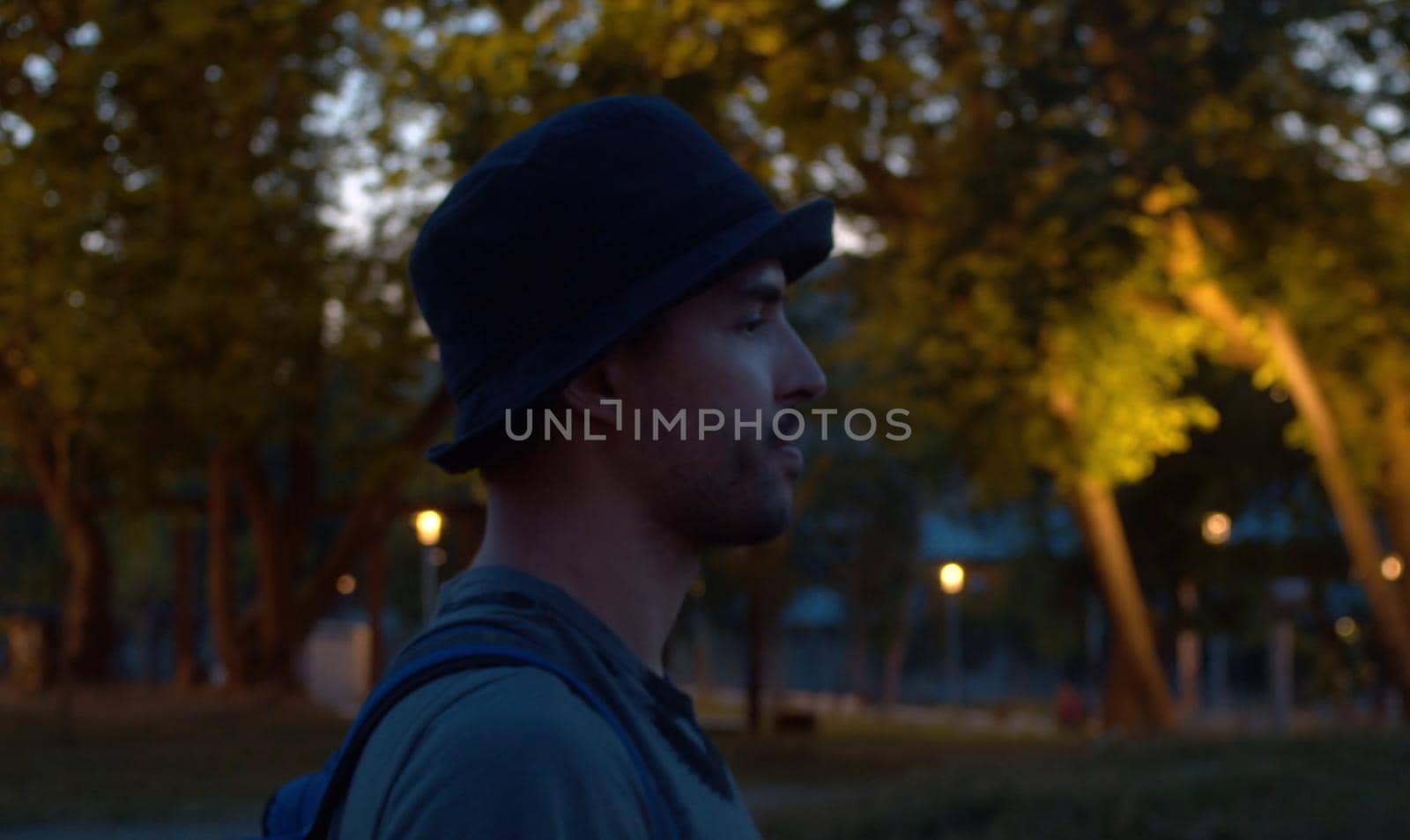 Portrait of a young man walking with a cigarette on the night city park background