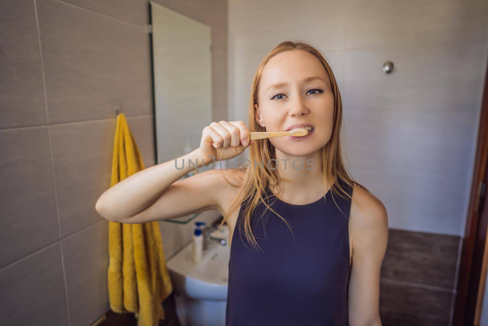 Young and caucasian woman brushing her teeth with a bamboo toothbrush.