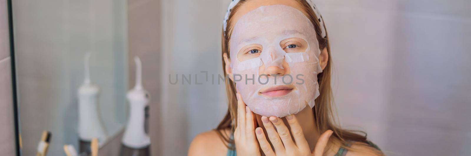 Young red-haired woman doing facial mask sheet. Beauty and Skin Care Concept BANNER, LONG FORMAT by galitskaya
