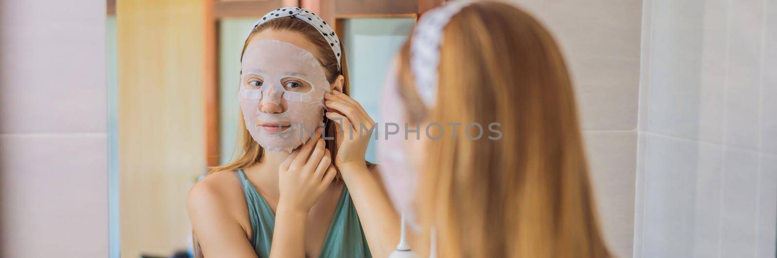 Young red-haired woman doing facial mask sheet. Beauty and Skin Care Concept BANNER, LONG FORMAT by galitskaya