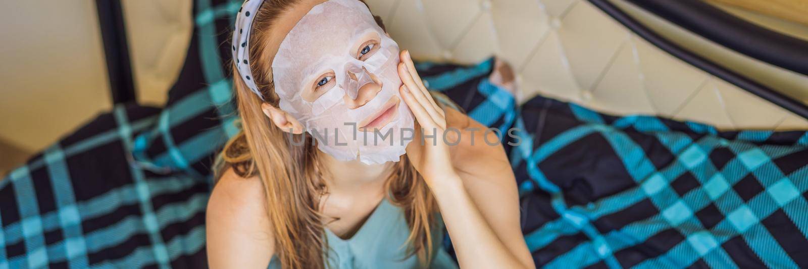 Young red-haired woman doing facial mask sheet. Beauty and Skin Care Concept. BANNER, LONG FORMAT