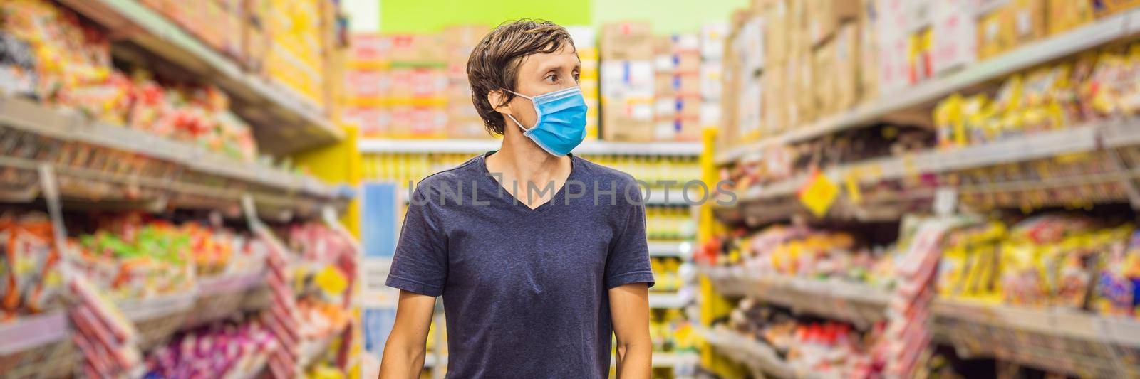 Alarmed man wears medical mask against coronavirus while grocery shopping in supermarket or store- health, safety and pandemic concept - young woman wearing protective mask and stockpiling food. BANNER, LONG FORMAT