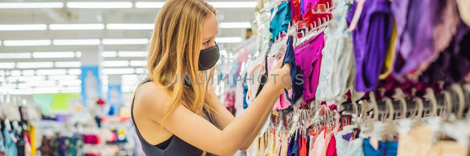 A woman in a clothing store in a medical mask because of a coronovirus. Quarantine is over, now you can go to the clothing store. BANNER, LONG FORMAT