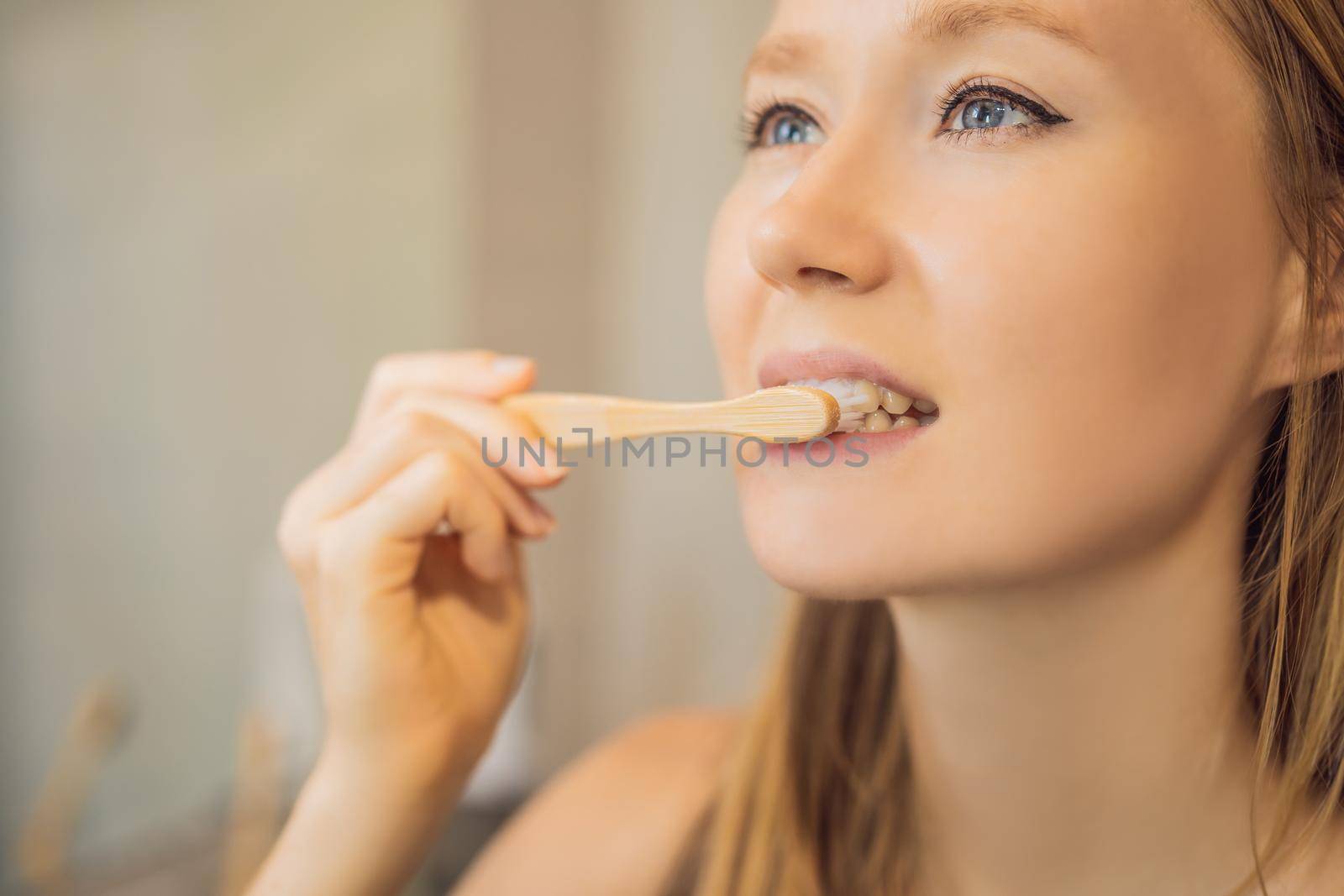 Young and caucasian woman brushing her teeth with a bamboo toothbrush.