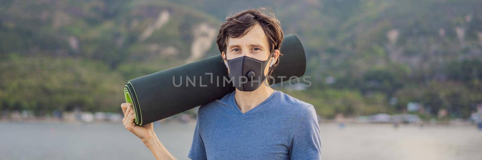 Young man in medical mask performing some workouts in the park during coronavirus quarantine, Coronavirus pandemic Covid-19. Sport, Active life in quarantine surgical sterilizing face mask protection. Outdoor run on athletics track in Corona Outbreak. BANNER, LONG FORMAT