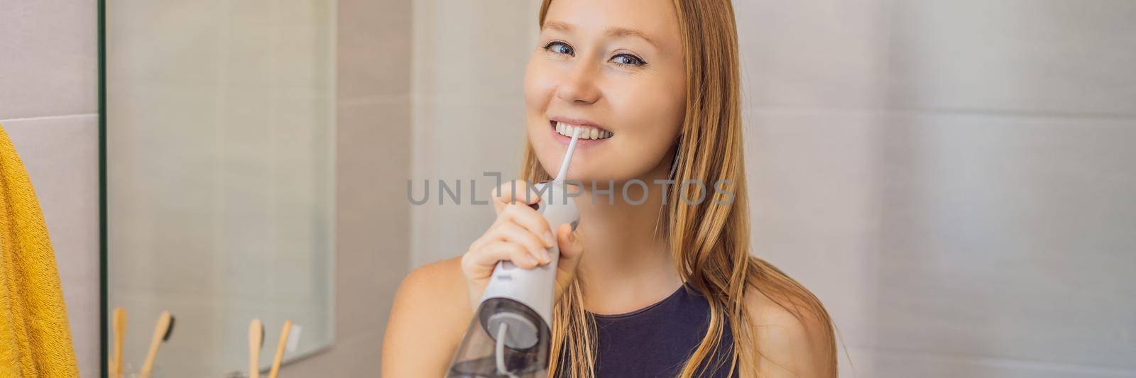 Woman using an oral irrigator in bathroom BANNER, LONG FORMAT by galitskaya