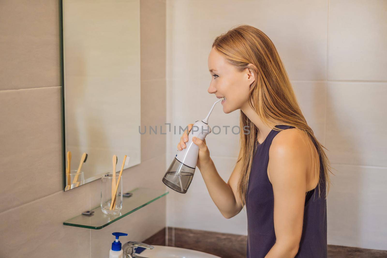 Woman using an oral irrigator in bathroom.