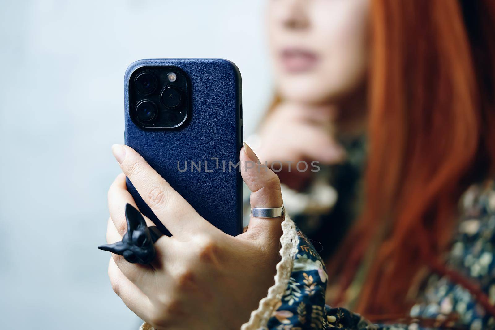 Female's hand with gothic ring holding smartphone in blue case. Woman blogger takes selfie on iPhone 13 pro. Focus on foreground. Gadget with triple-lens camera. Bishkek, Kyrgyzstan - January 24, 2022