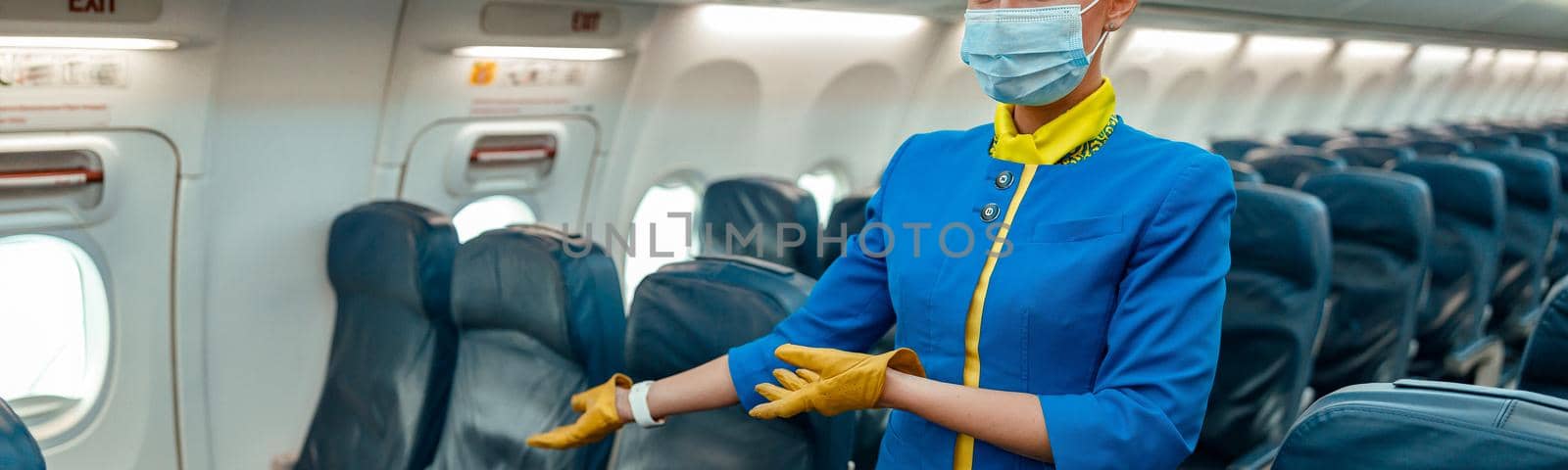 Stewardess in face mask inviting to take passenger seat in plane by Yaroslav_astakhov