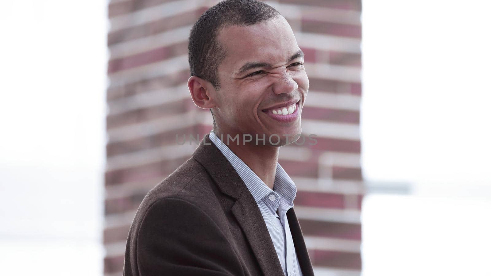 smiling young businessman on background of office. by SmartPhotoLab
