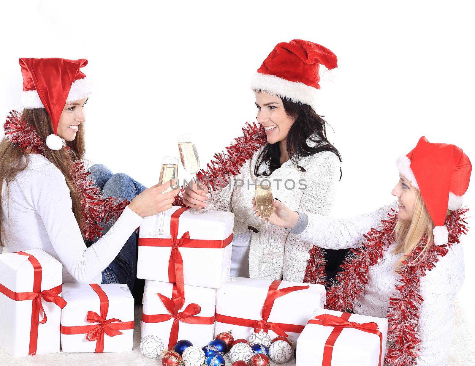 three young women in hats of Santa Claus with Christmas gifts and glasses of champagne.photo with copy space