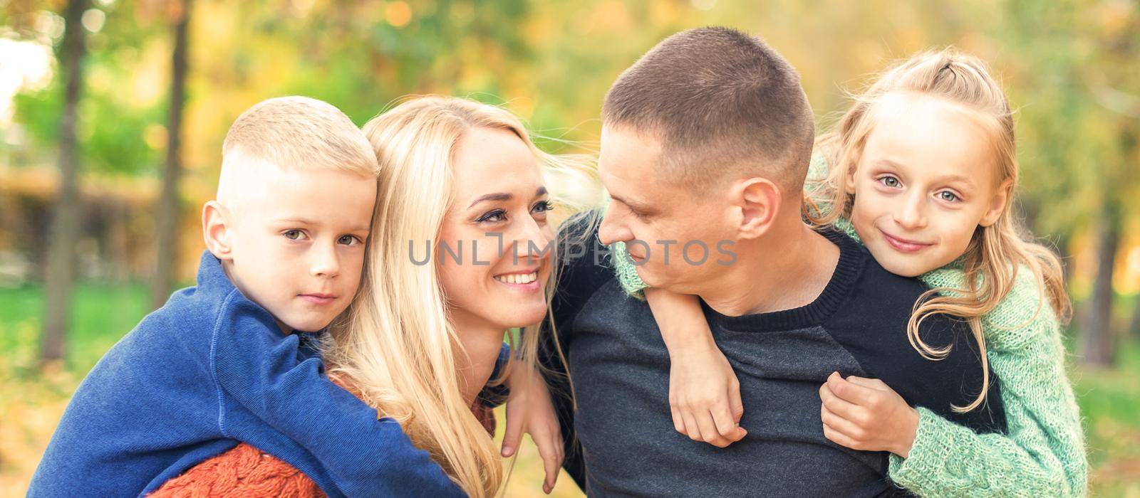 Portrait of young family playing in autumn park. Parents with children resting in the autumn park