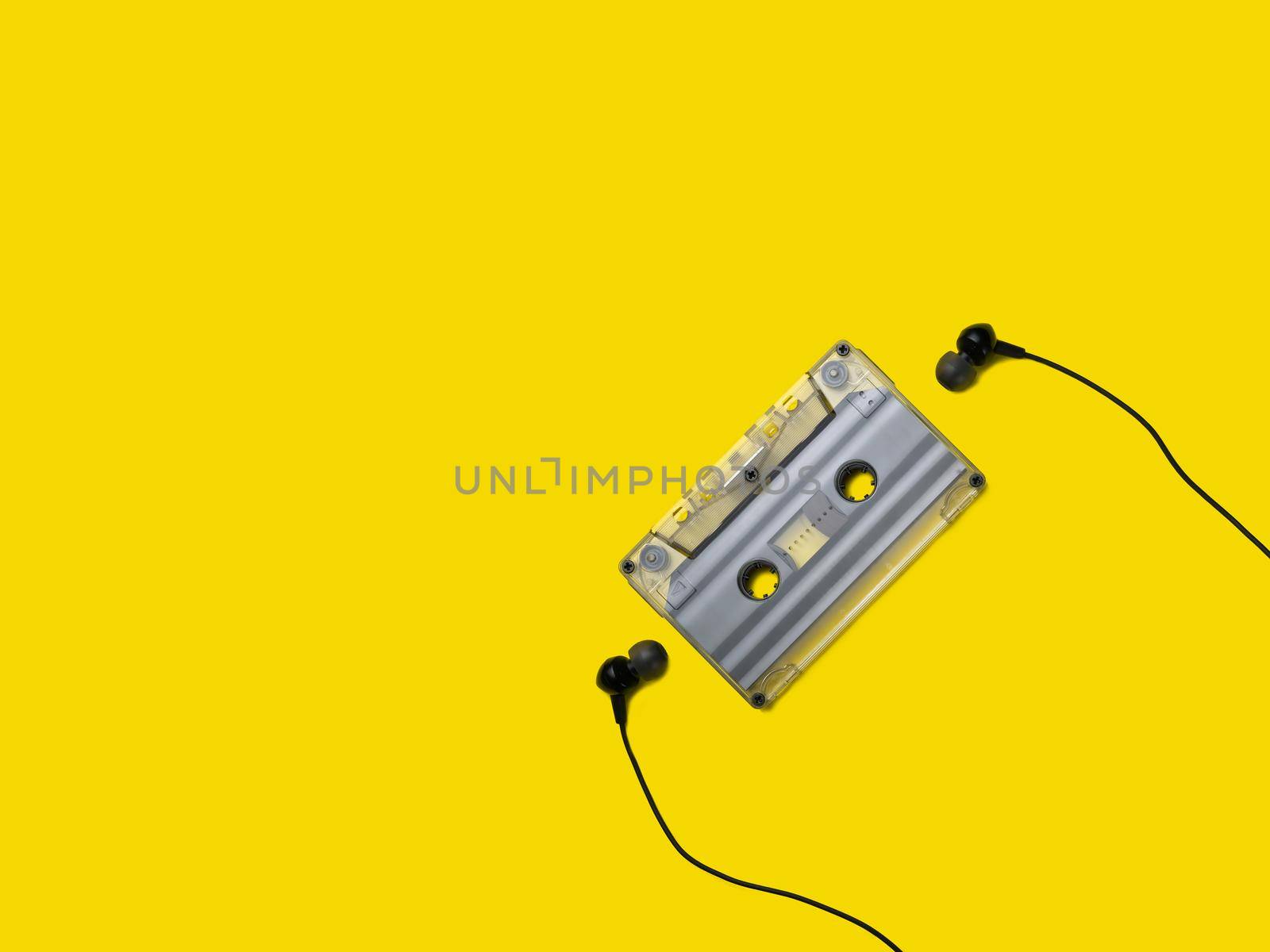 Headphones and old audio cassette on yellow background