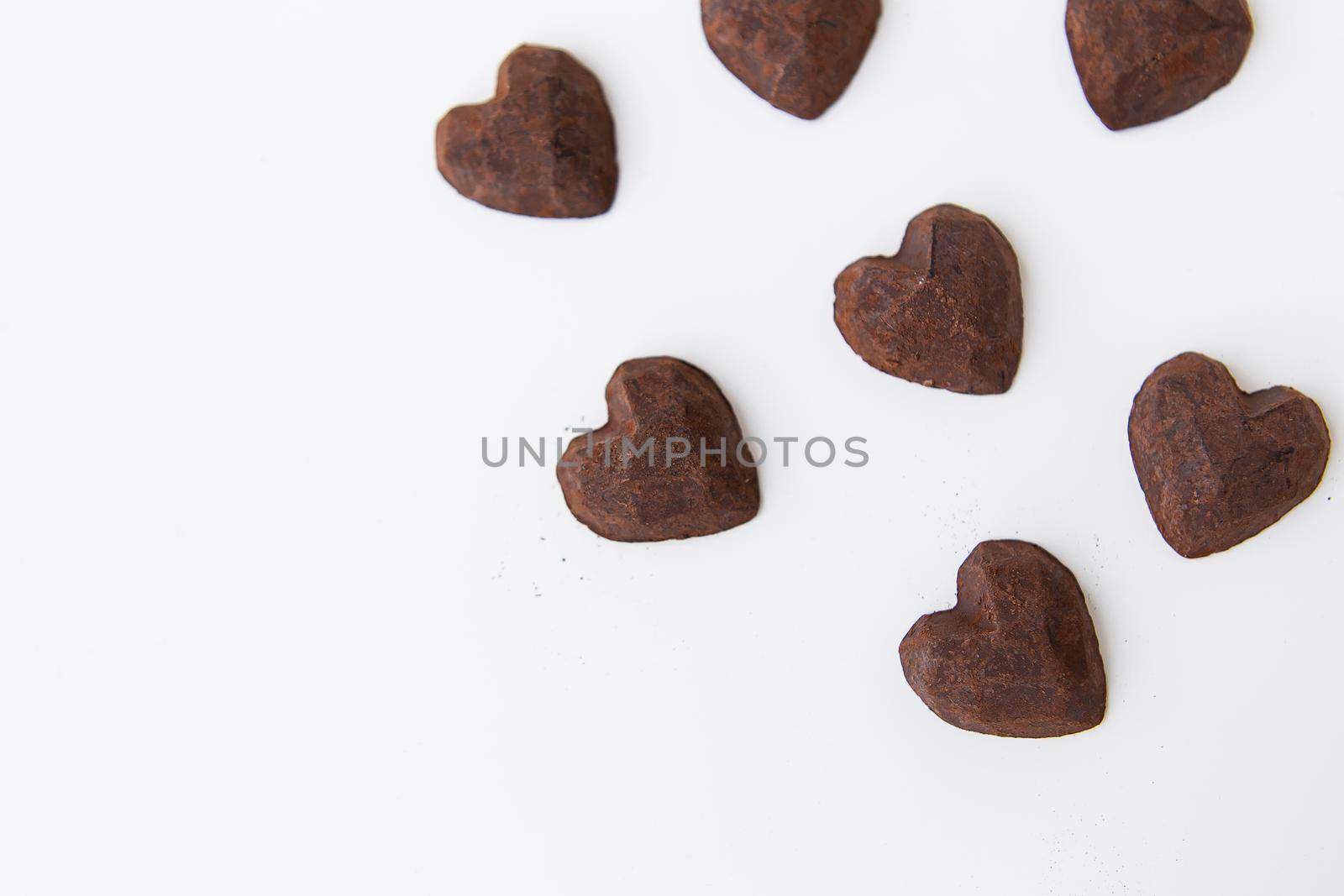 Chocolate candies with a truffle in the form of a heart on a white background, close-up. Place for an inscription. by sfinks