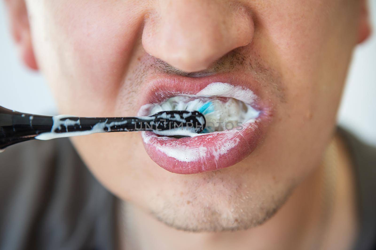 A man brushes his teeth with an electric toothbrush. The concept of daily hygiene and cleanliness