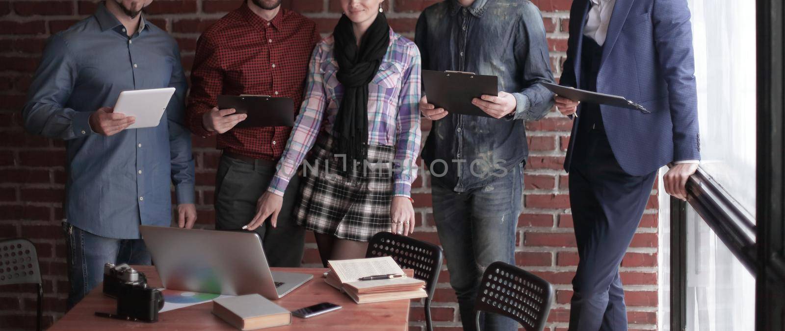 group of designers with a clipboard discuss the information standing in the Studio.