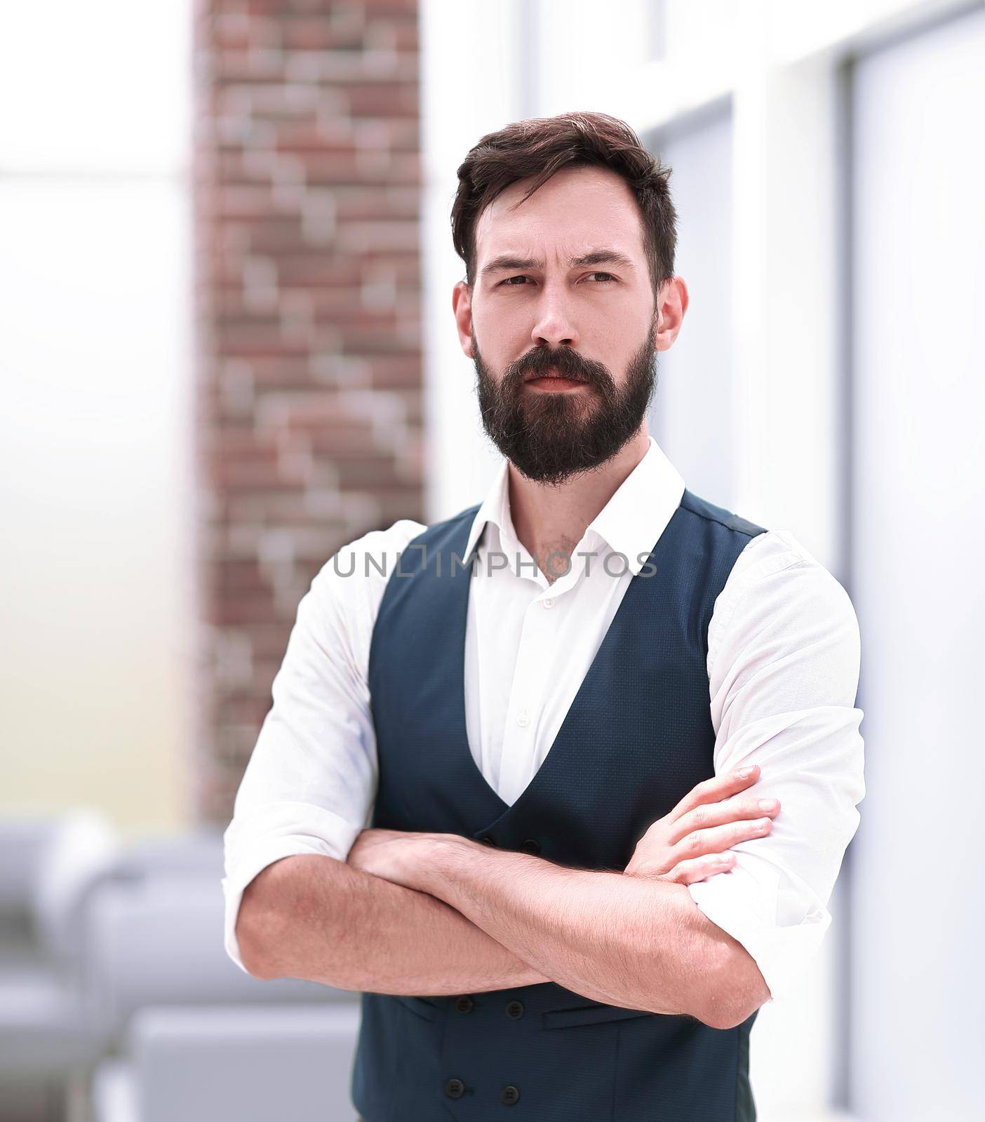 serious businessman standing in a modern office by SmartPhotoLab
