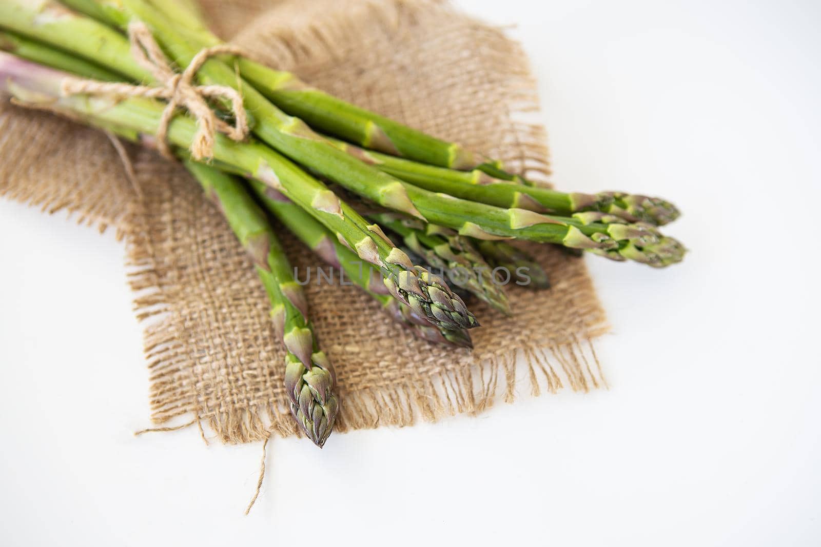 Fresh green asparagus tied with thread and lying on sacking. Healthy and wholesome food concept