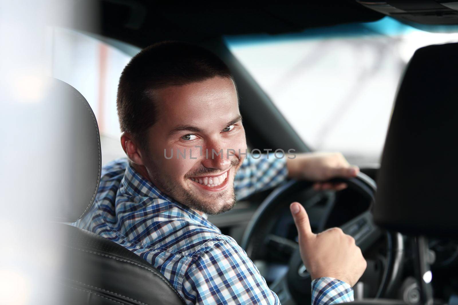 close up. modern man sitting in a car and showing his thumb up.