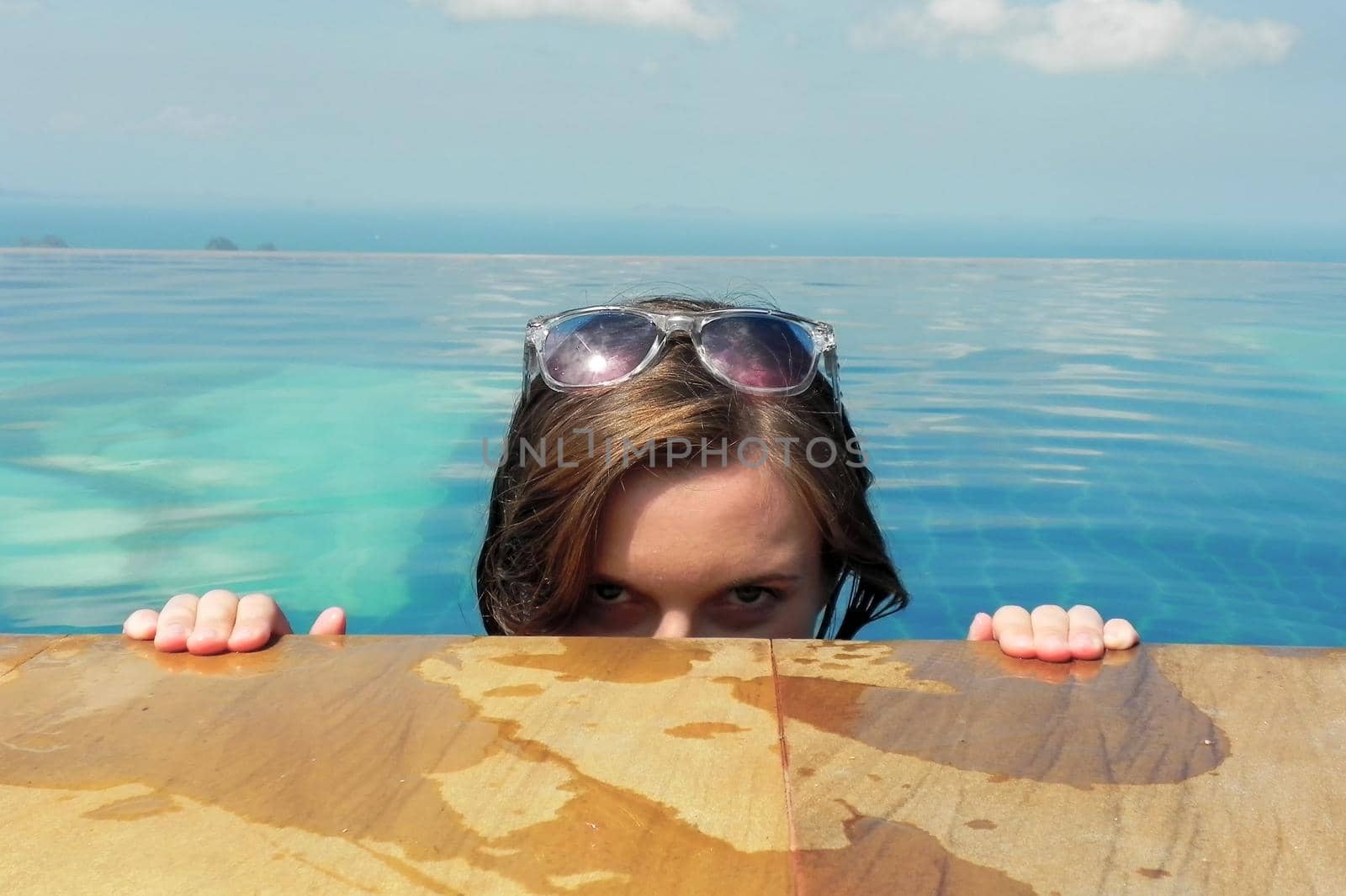 beautiful young european woman in the swimming pool near the ocean, spa, relaxing, tropical, vacation.