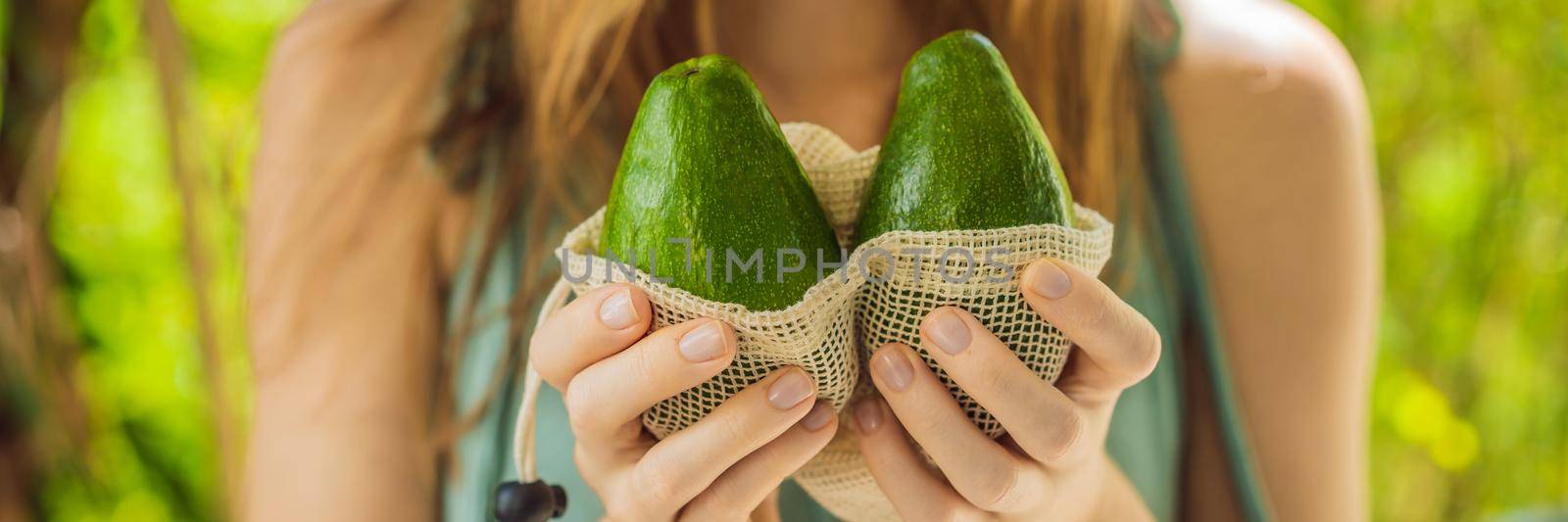 Avocado in a reusable bag in the hands of a young woman. Zero waste concept. BANNER, LONG FORMAT