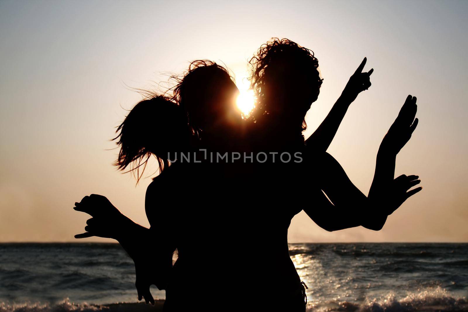 Group of young women having fun on the beach at sunset. Girls silhouettes outdoor