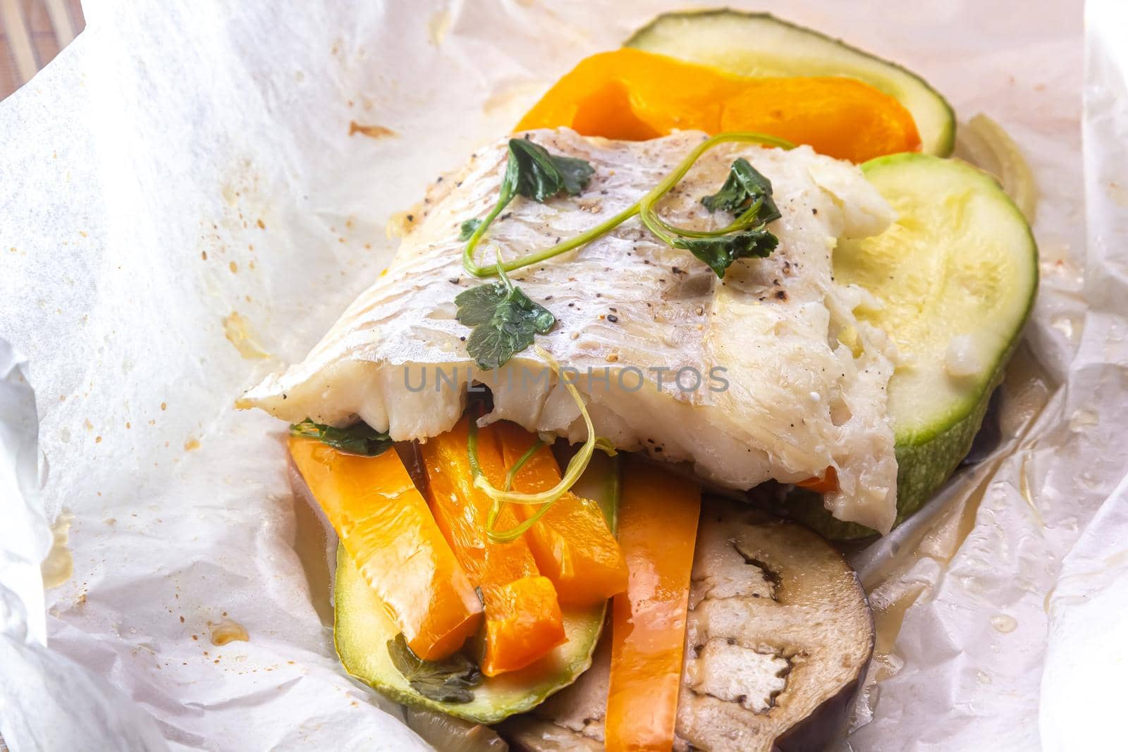 White fish fillet with vegetables in rustic style. Healthy eating: cooked fish fillet with vegetables garnish. Diet food with white fish and vegetables. Steam vegetables with roasted zander fillet.