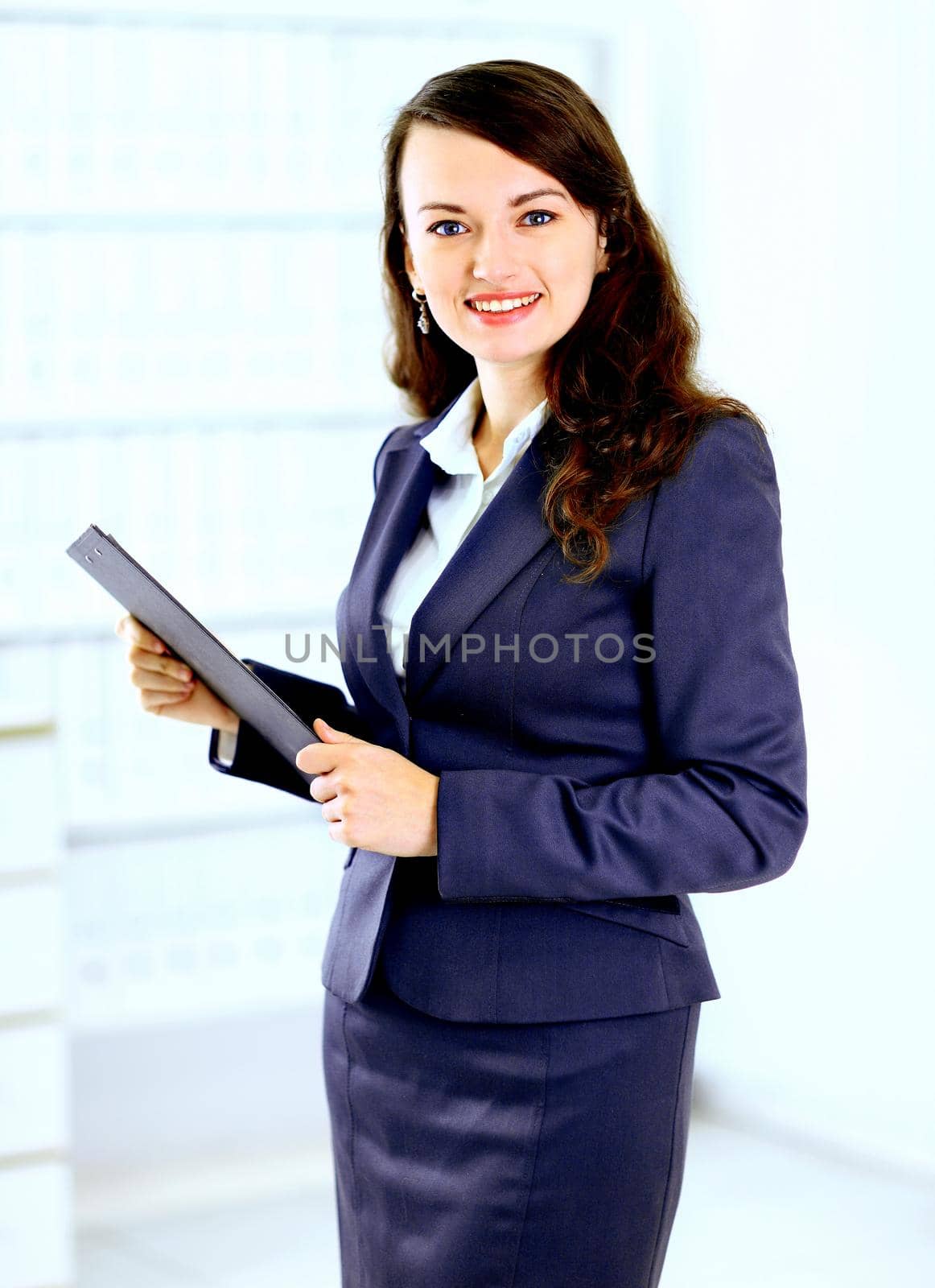 Portrait of a cute young business woman with the work plan smiling, in an office environment.