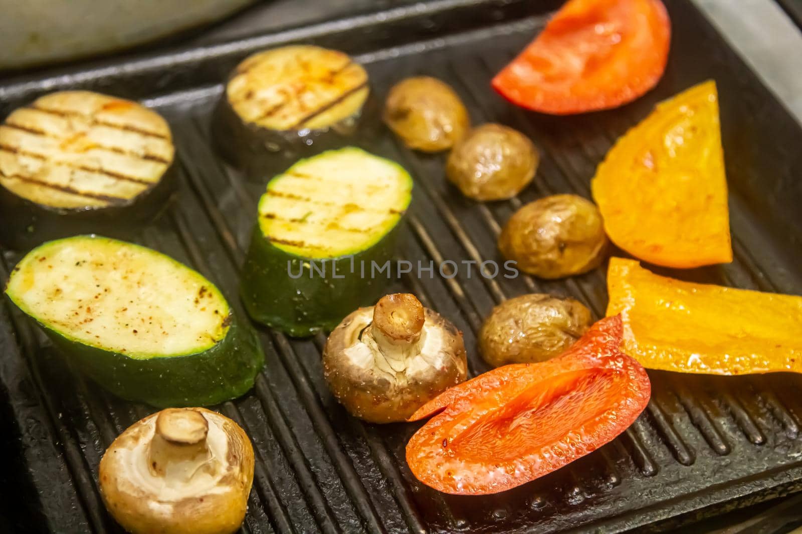 Grilled vegetables: tomatoes, corn, eggplant, zucchini, mushrooms, sweet peppers are prepared in a professional grill machine. Chef grills vegetables in the restaurant kitchen by Milanchikov